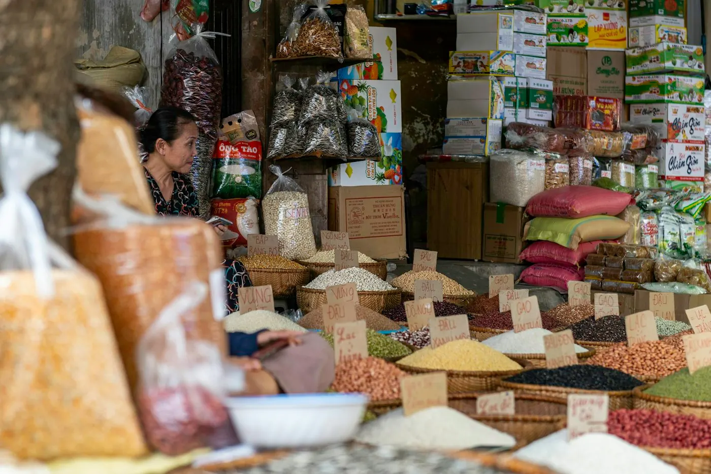Người bán hàng khô bên quầy gạo, đậu và hạt